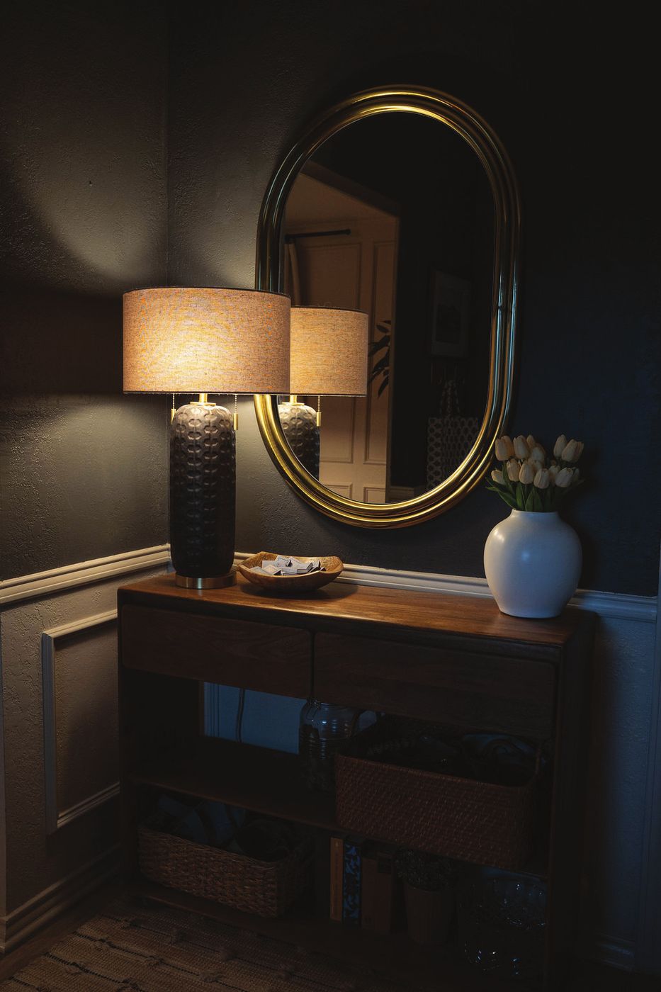 Entry with a brass oval mirror and textured lamp